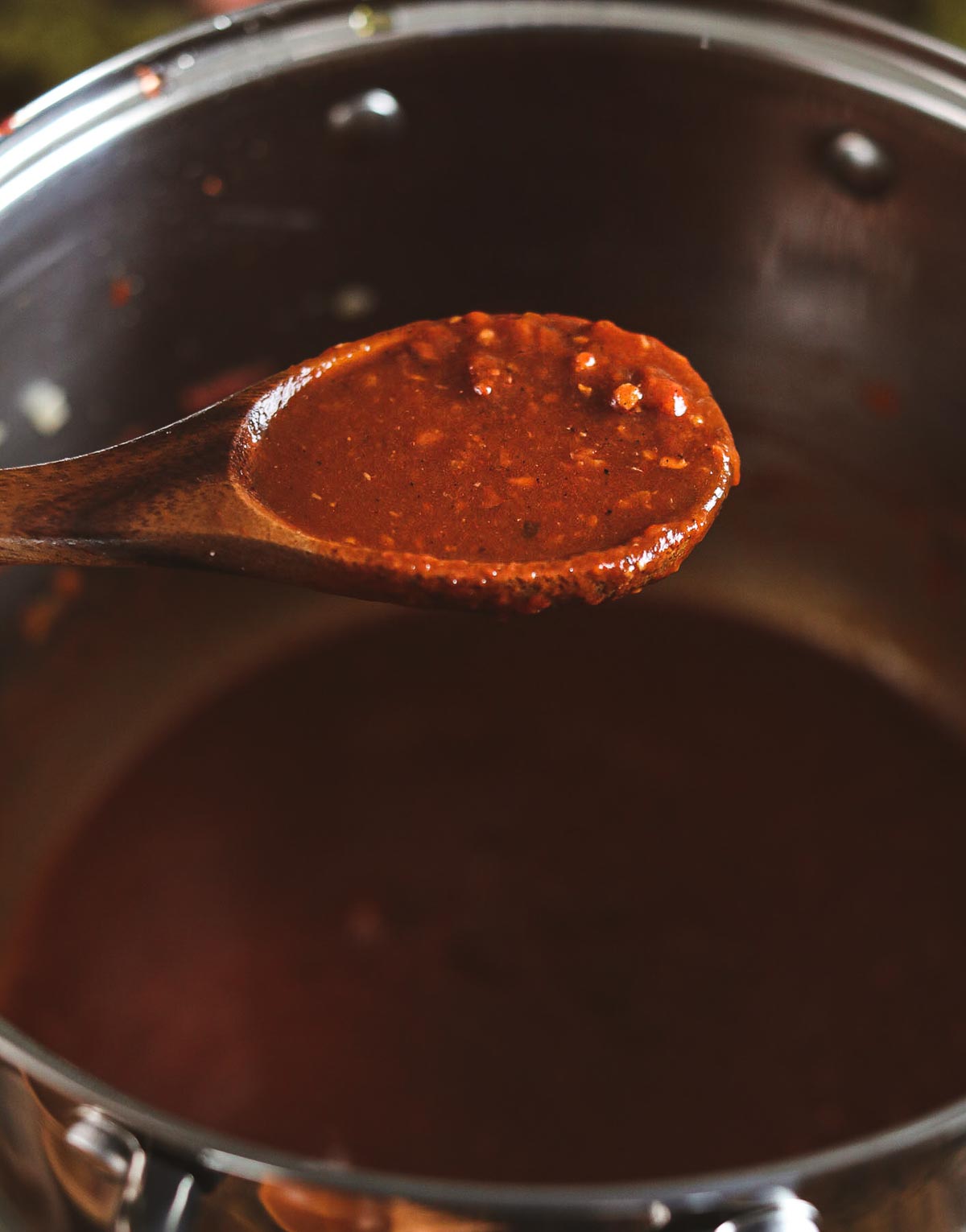 A close up of the thick red sauce on a wooden spoon.