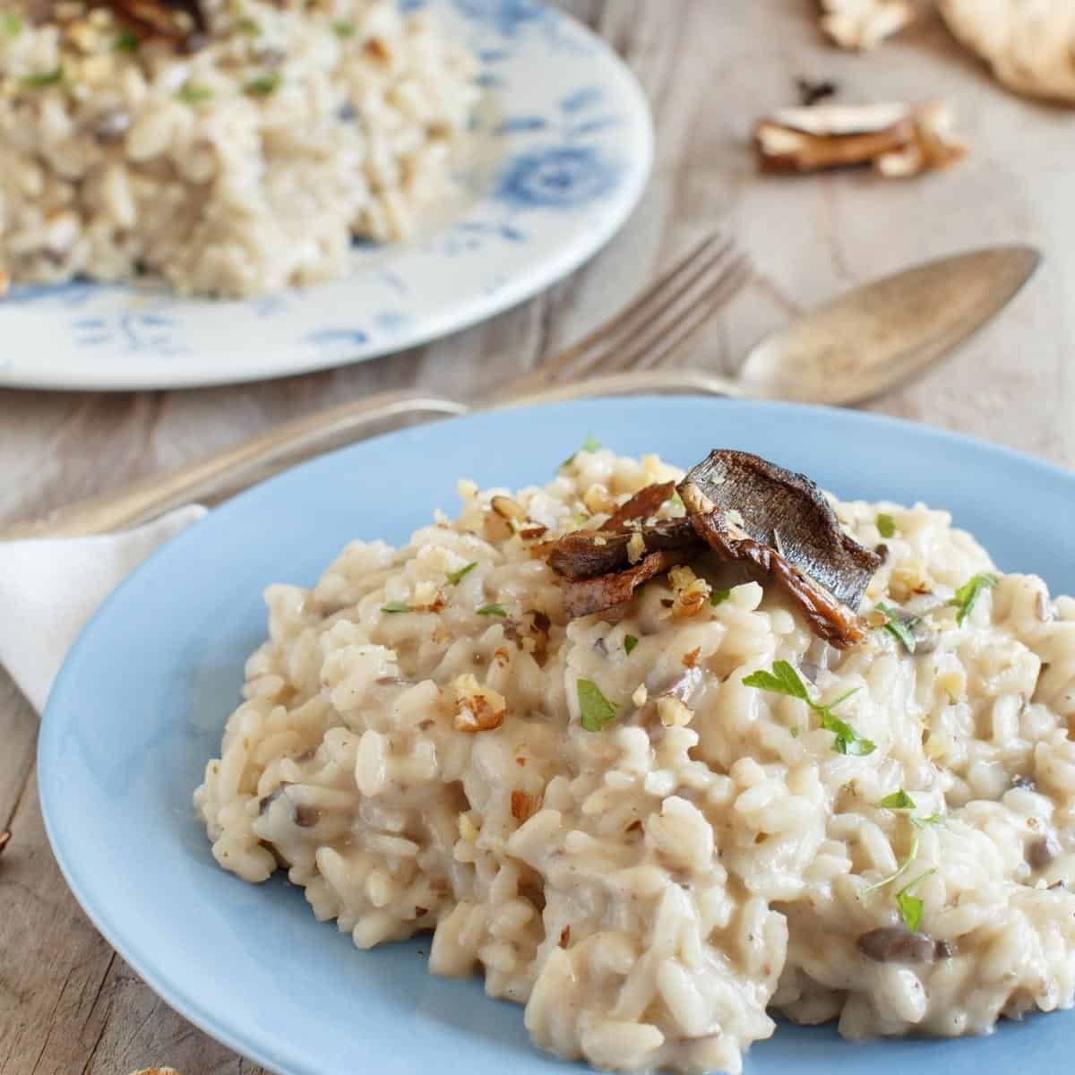 a plate of risotto on a blue plate sitting on a wooden table