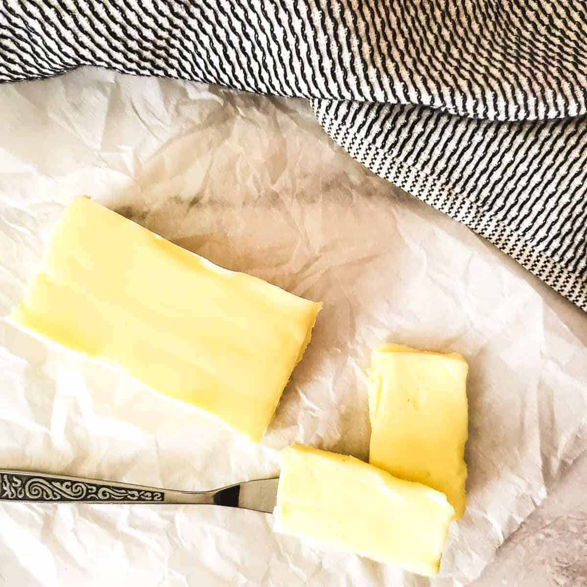 A rectangular block of homemade cultured butter on a crumpled piece of parchment paper next to a napkin.