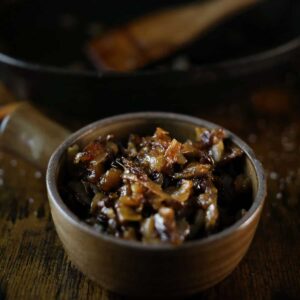 Smoked onions, caramelized, in a bowl on a wood table.