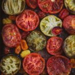 Smoked tomatoes of different varieties and colors on a baking tray.