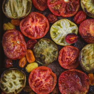 Smoked tomatoes of different varieties and colors on a baking tray.