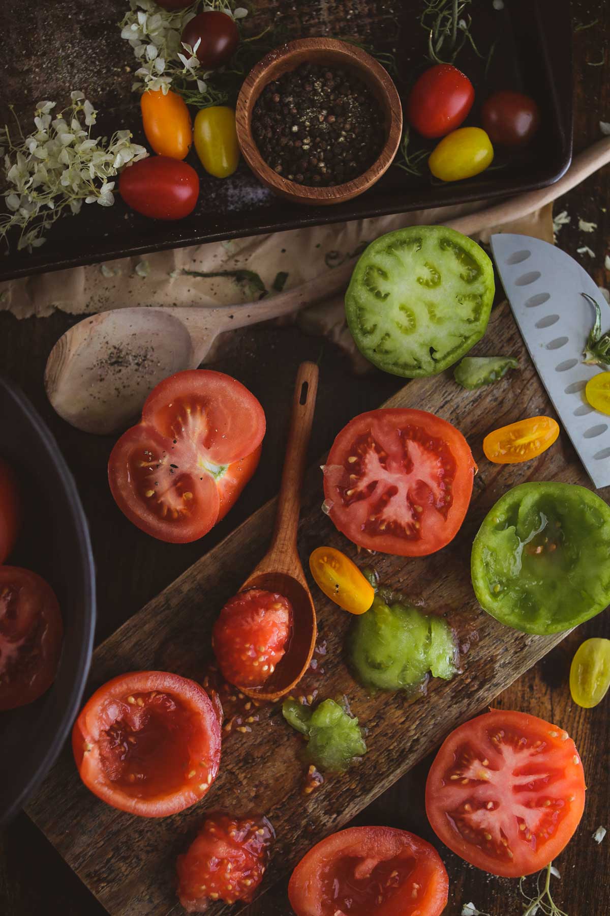 Tomatoes having their seeds removed on a wooden cutting board.