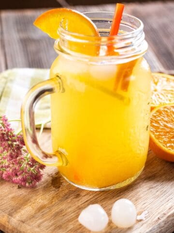 A mason jar with a refreshing blend of citrus and other rehydrating ingredients. It's on a wooden table.