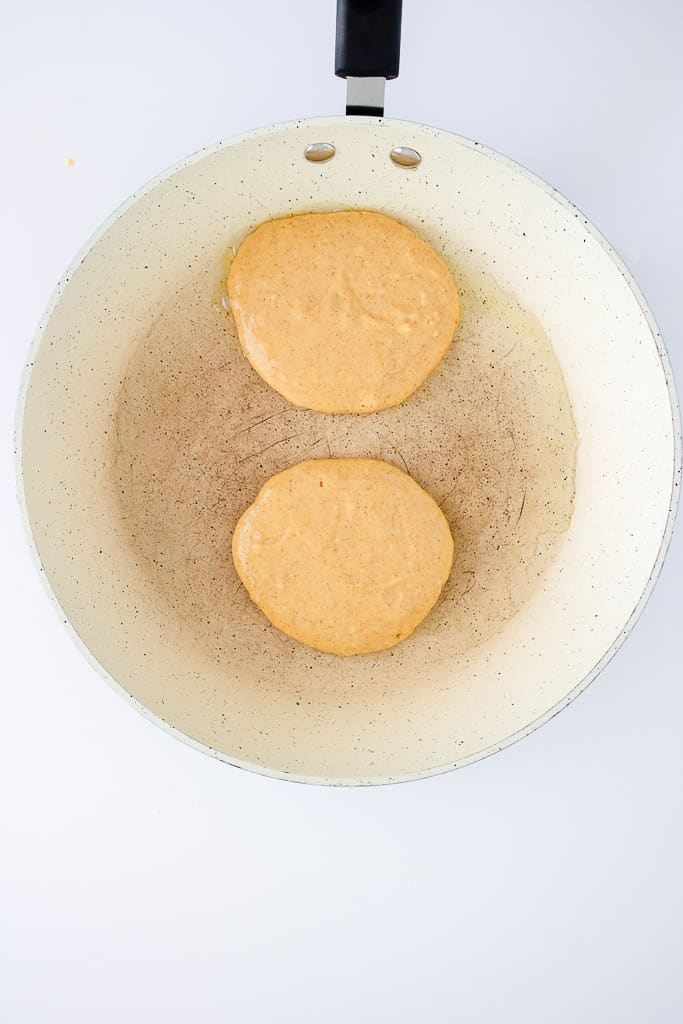 a frying pan with two pancakes being cooked