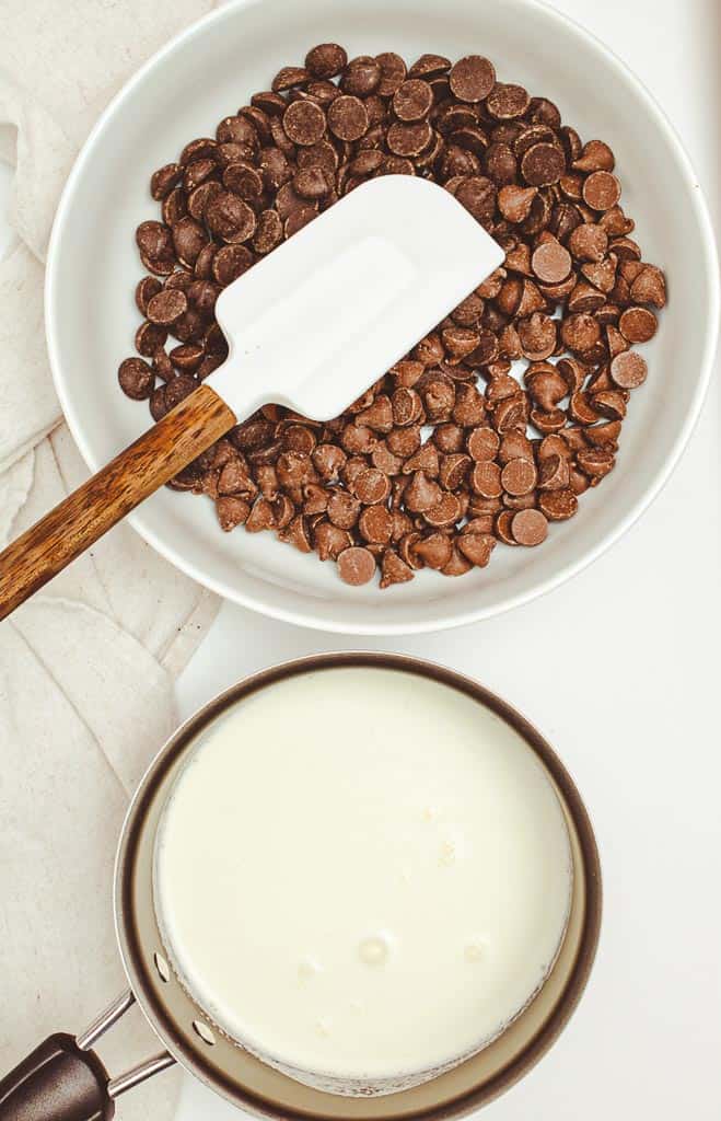 A saucepan of milk next to a bowl of chocolate chips.