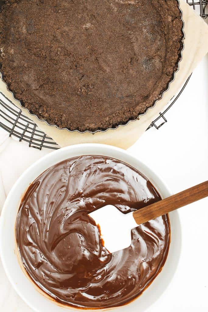 The baked and cooled tart crust next to thickened chocolate  ganache.