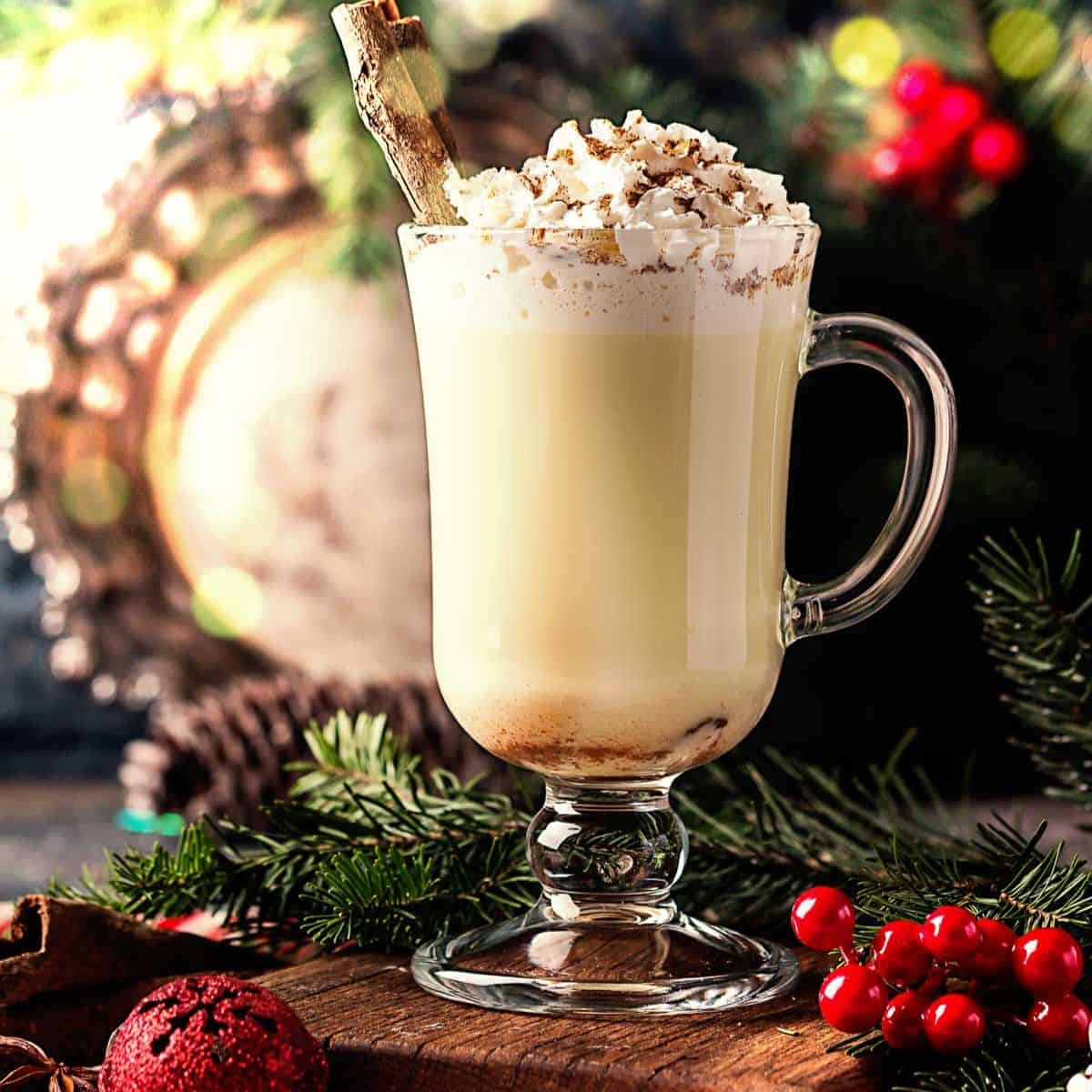 a tall glass of traditional aged eggnog topped with whipped cream and grated nutmeg.
