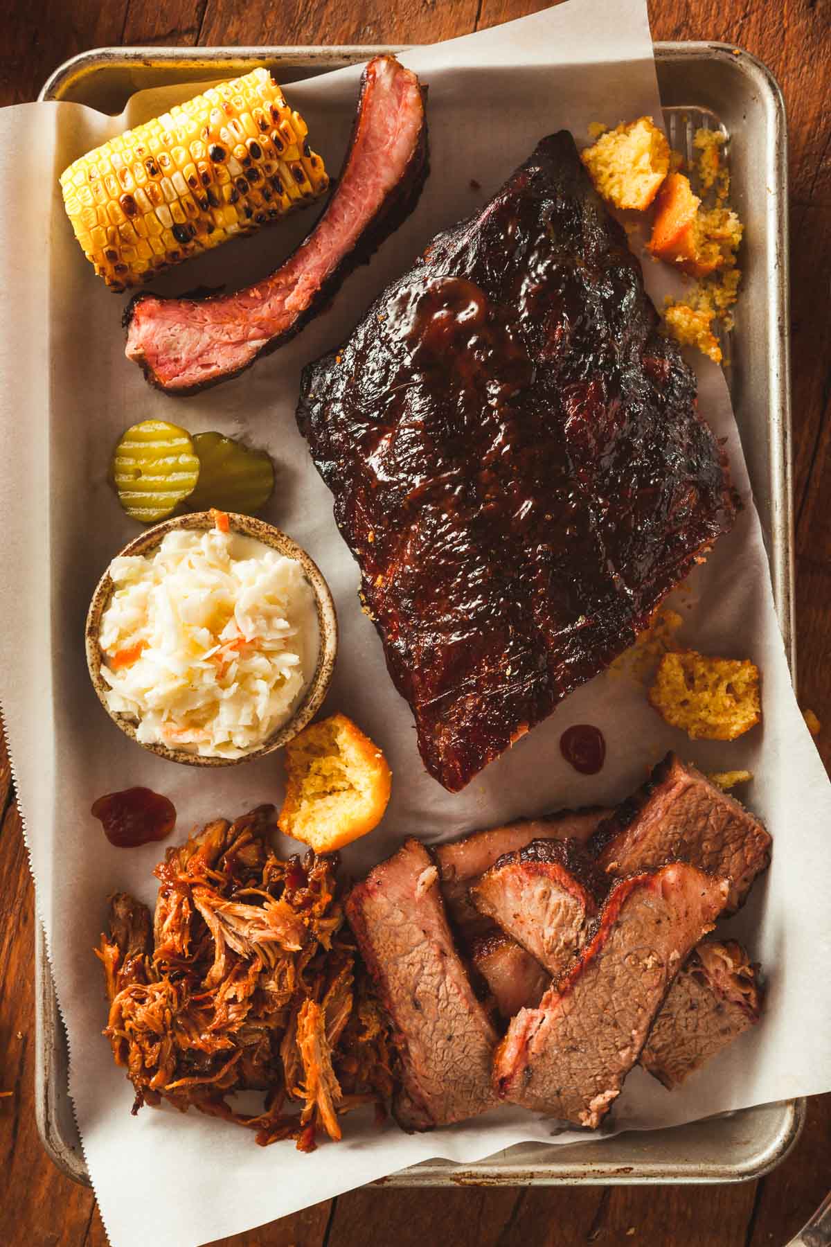 A BBQ meat platter perfect for one adult: half a rack of ribs next to a small serving of pulled pork, brisket, and traditional sides like coleslaw and pickles.