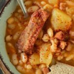 A bowl full of grah stew with white beans, potatoes, carrots, and smoked pork ribs.