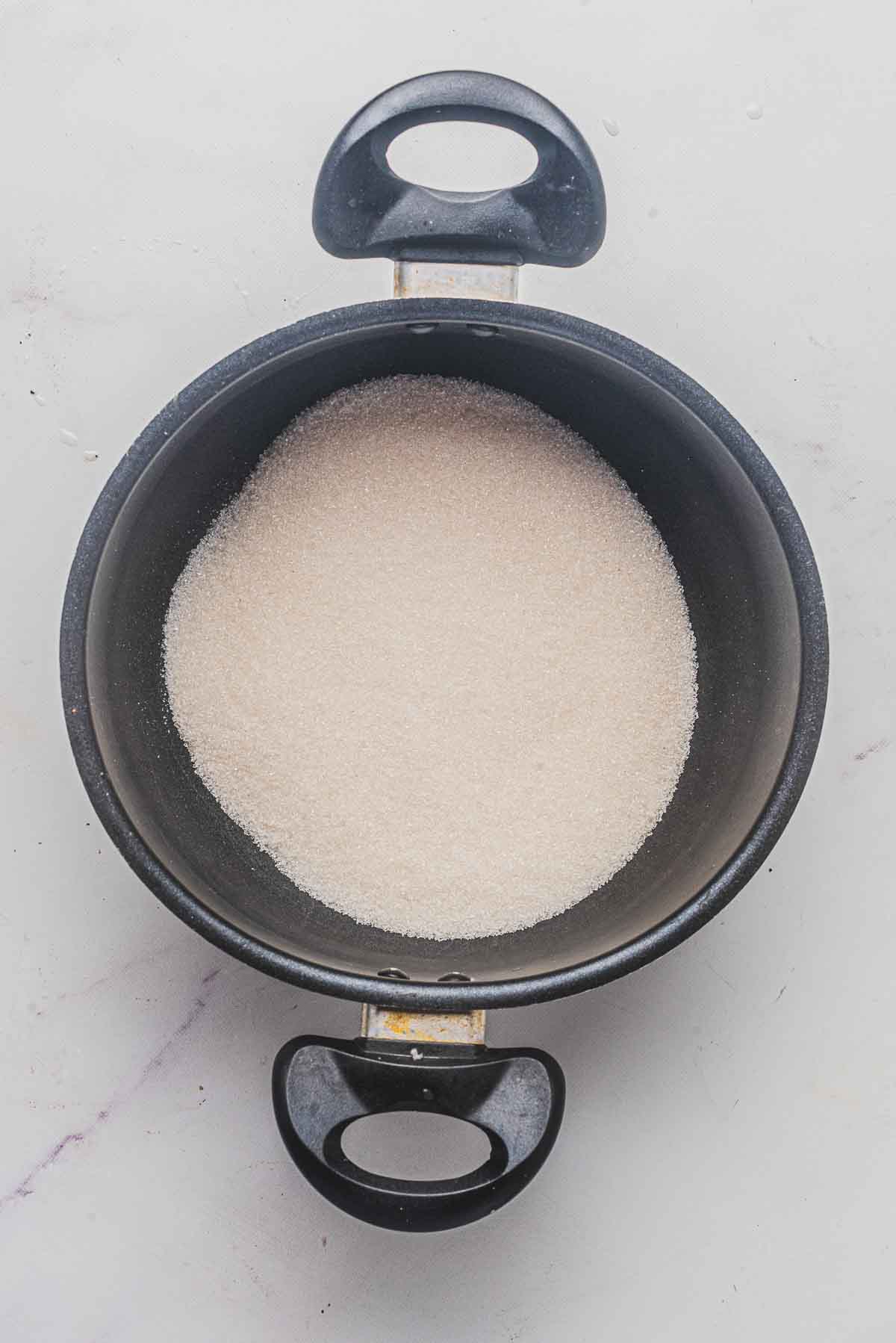 A saucepan filled with white granulated sugar.