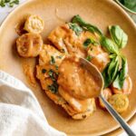Creamy, crock pot chicken breasts on a light brown plate. They are smothered in extra sauce.