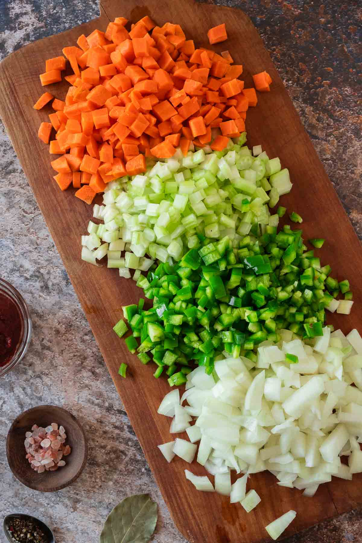 Diced and prepped vegetables on a wooden board.
