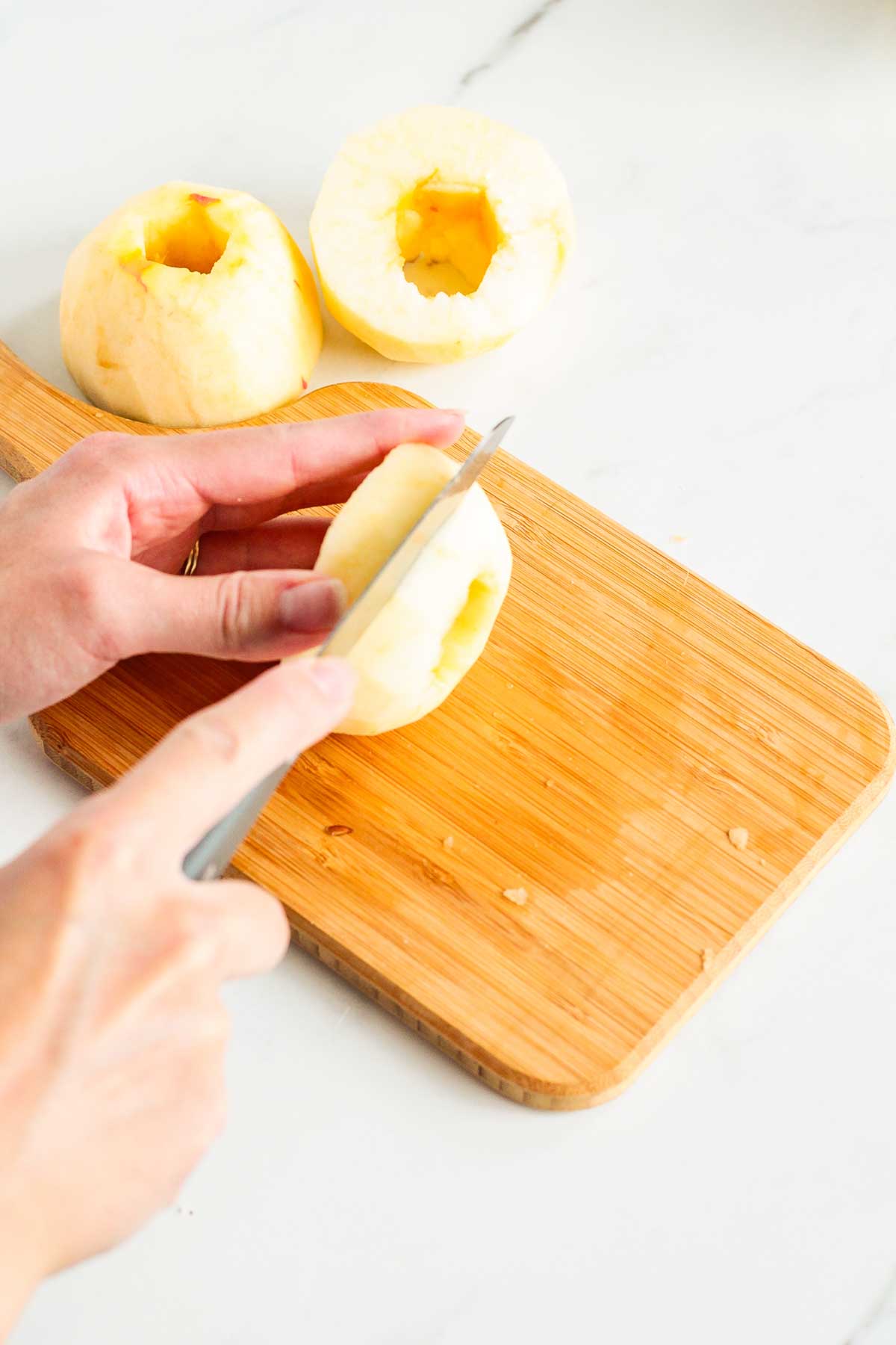 A cored apple being sliced to make apple fritter rings.