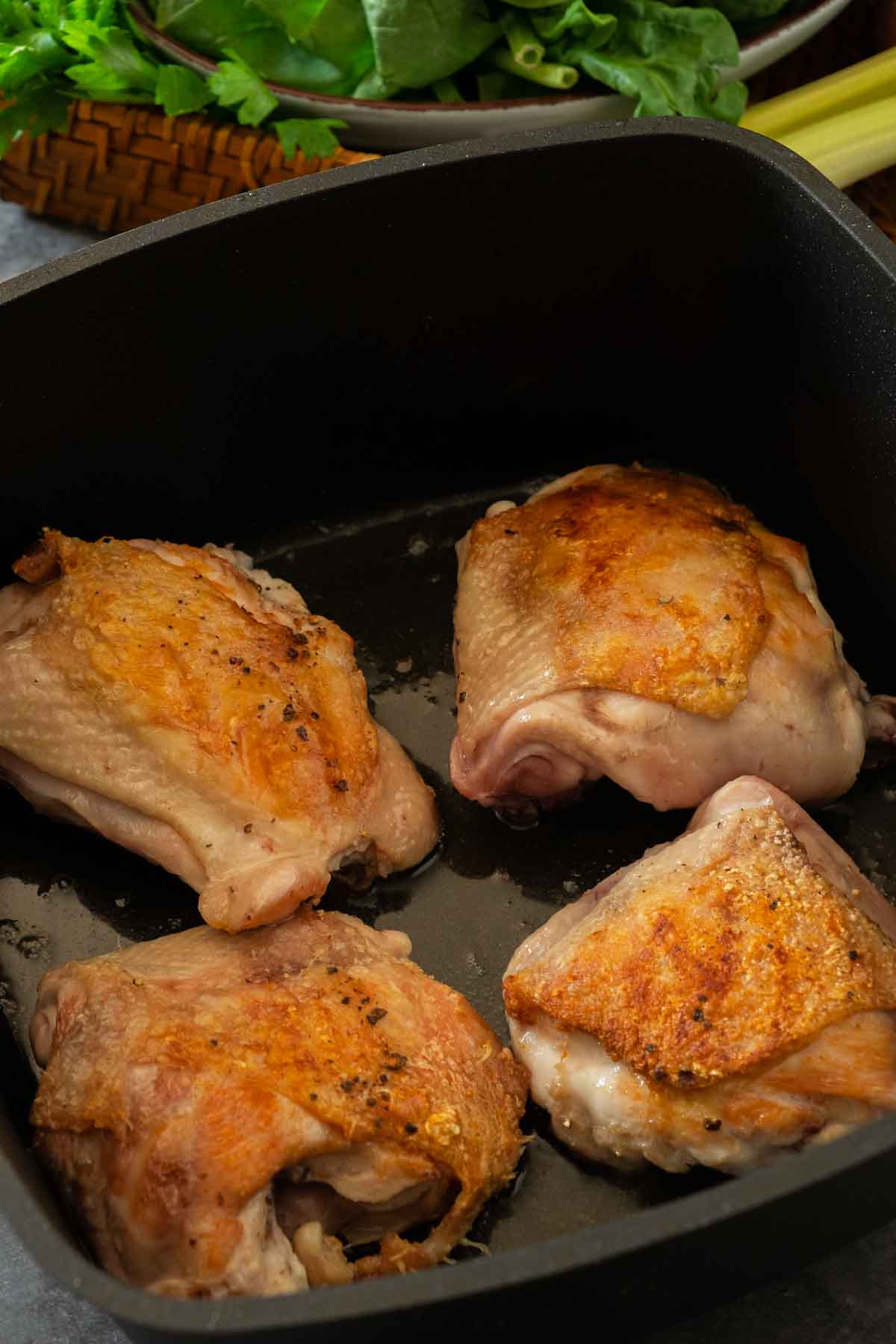 Crispy, browned skin-on chicken thighs in a large pot.