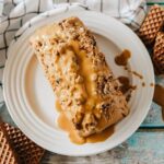 A brown loaf of nutter butter ice cream bread topped with melted creamy peanut butter.