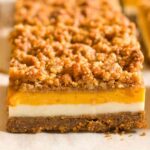 The finished layered pumpkin bars on parchment paper. Each layer is clearly defined and neatly layered.