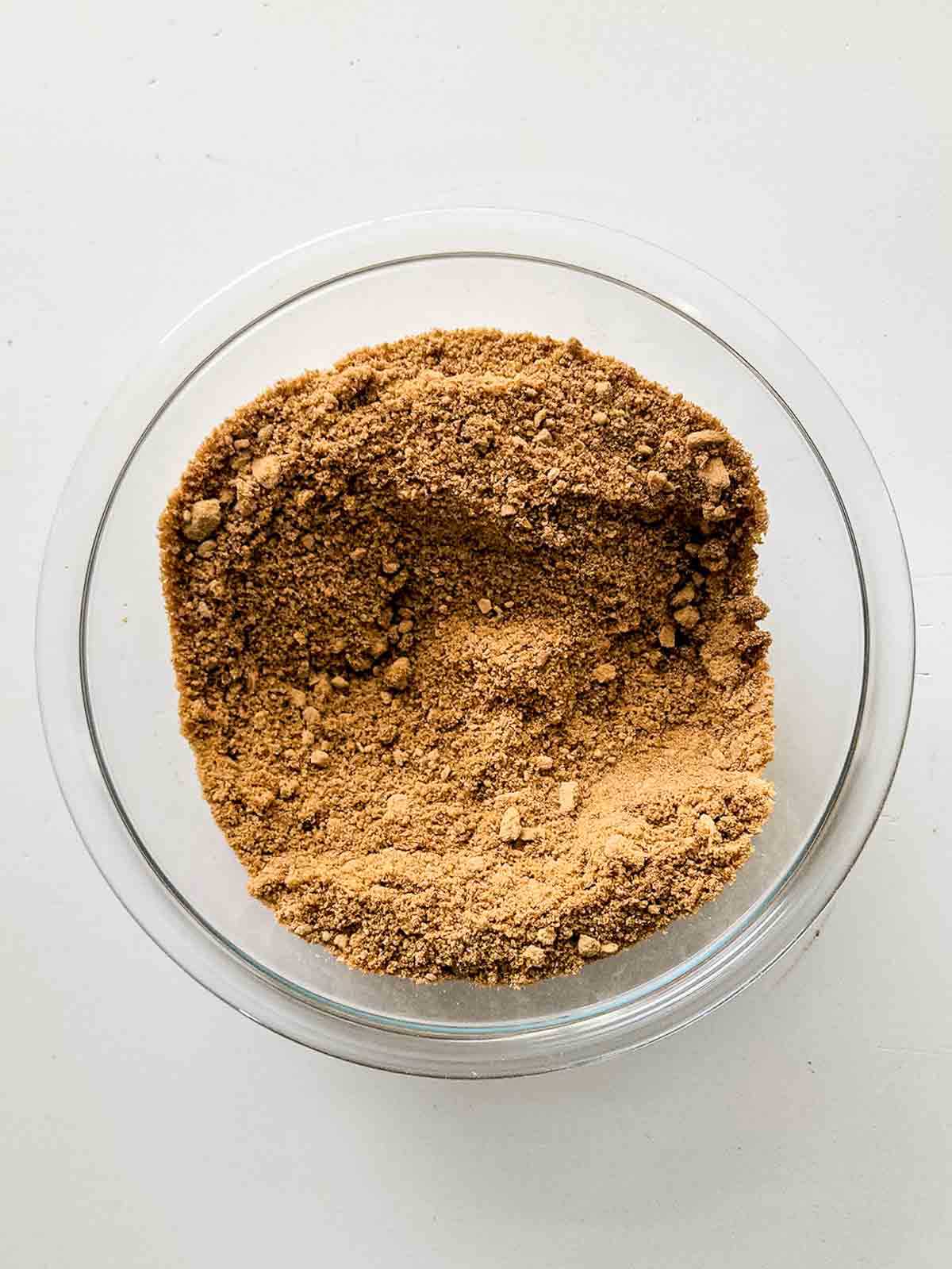 Brown, dry ingredients in a glass bowl after mixing.
