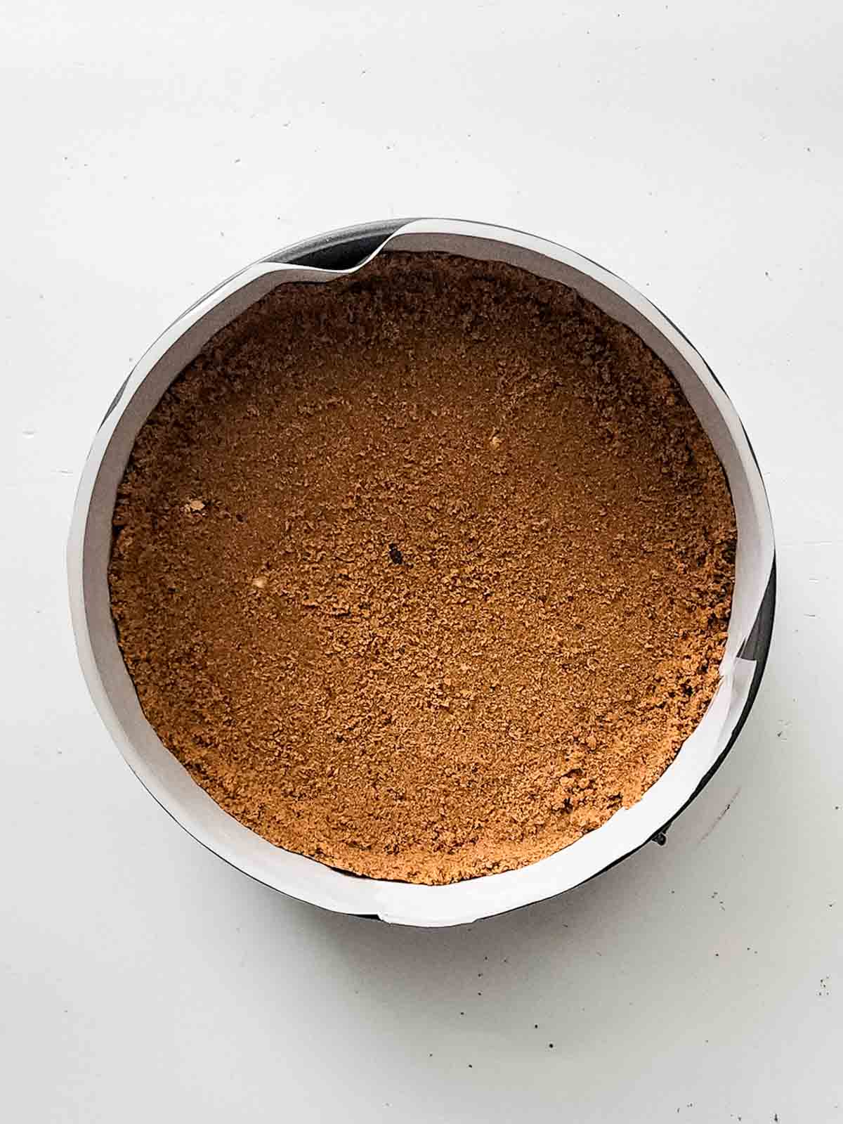 The flattened crust in the lined cake pan.