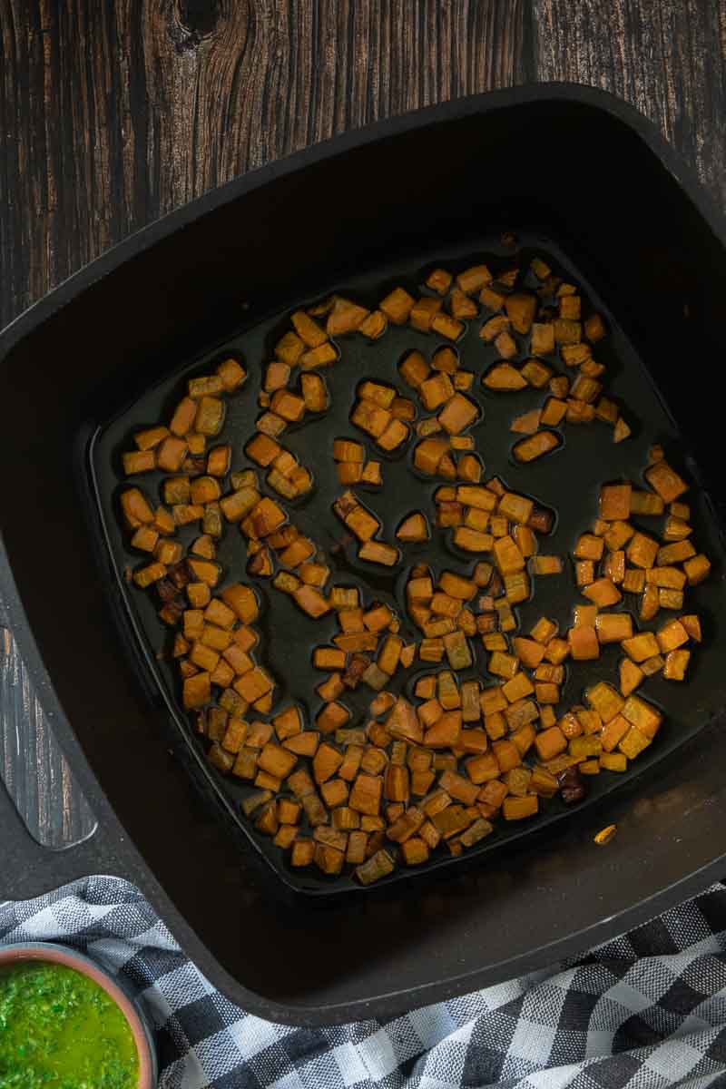 Diced carrots sautéing in a heavy black pot.