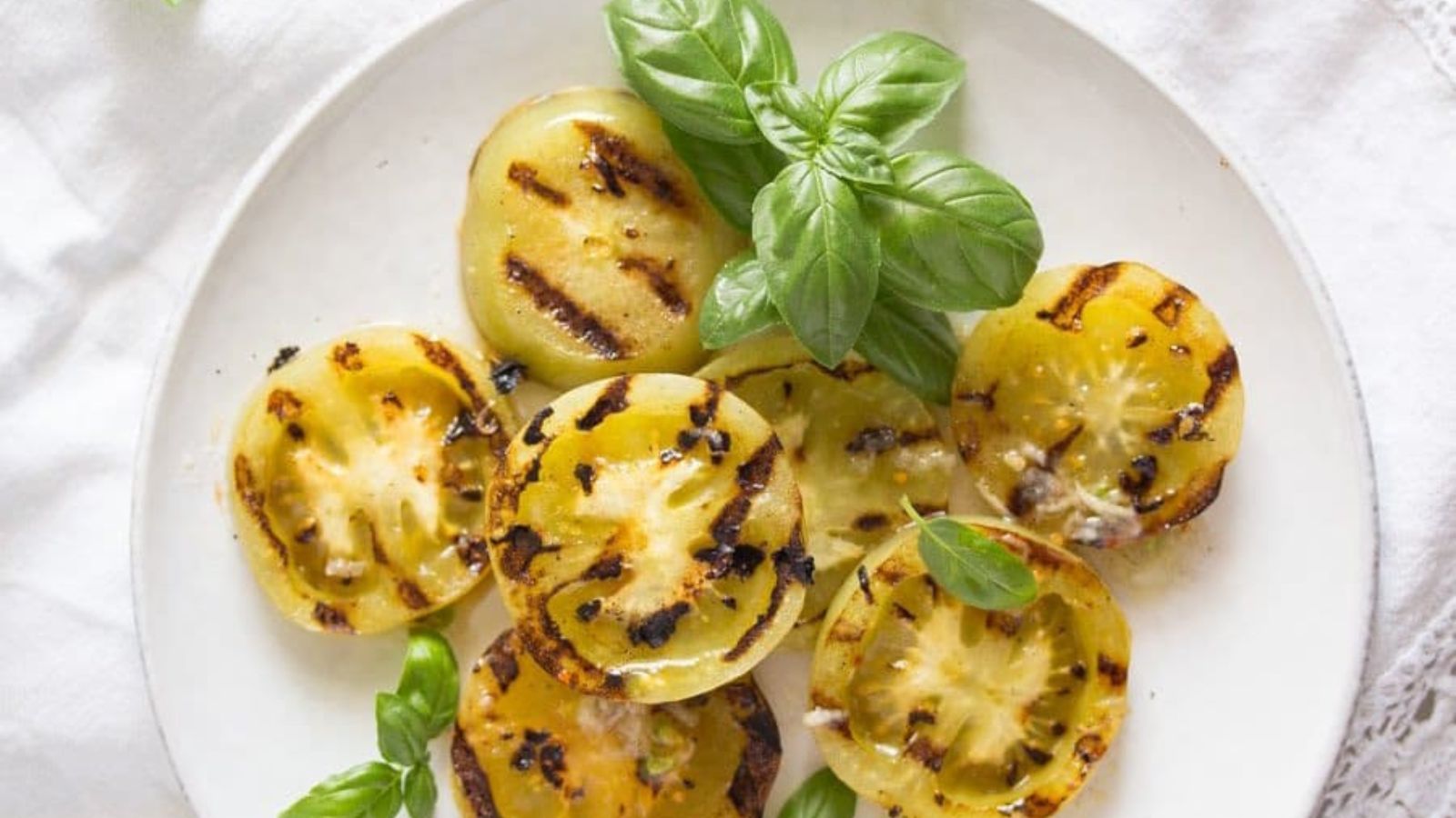 Grilled green tomatoes on a white plate.