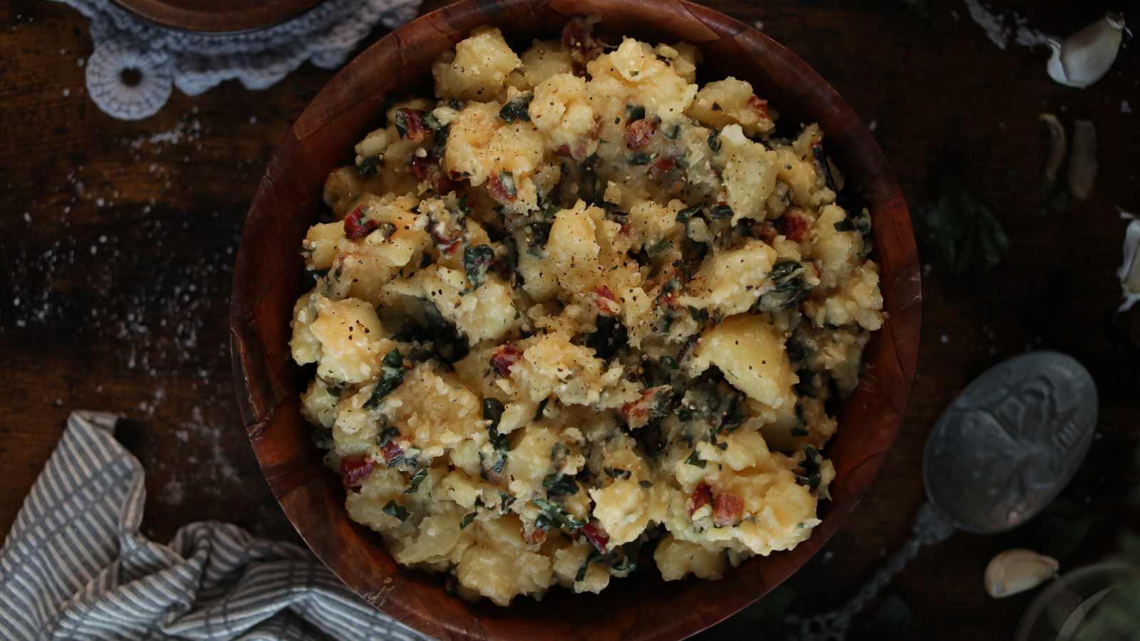 A brown bowl full of potatoes and Swiss chard.