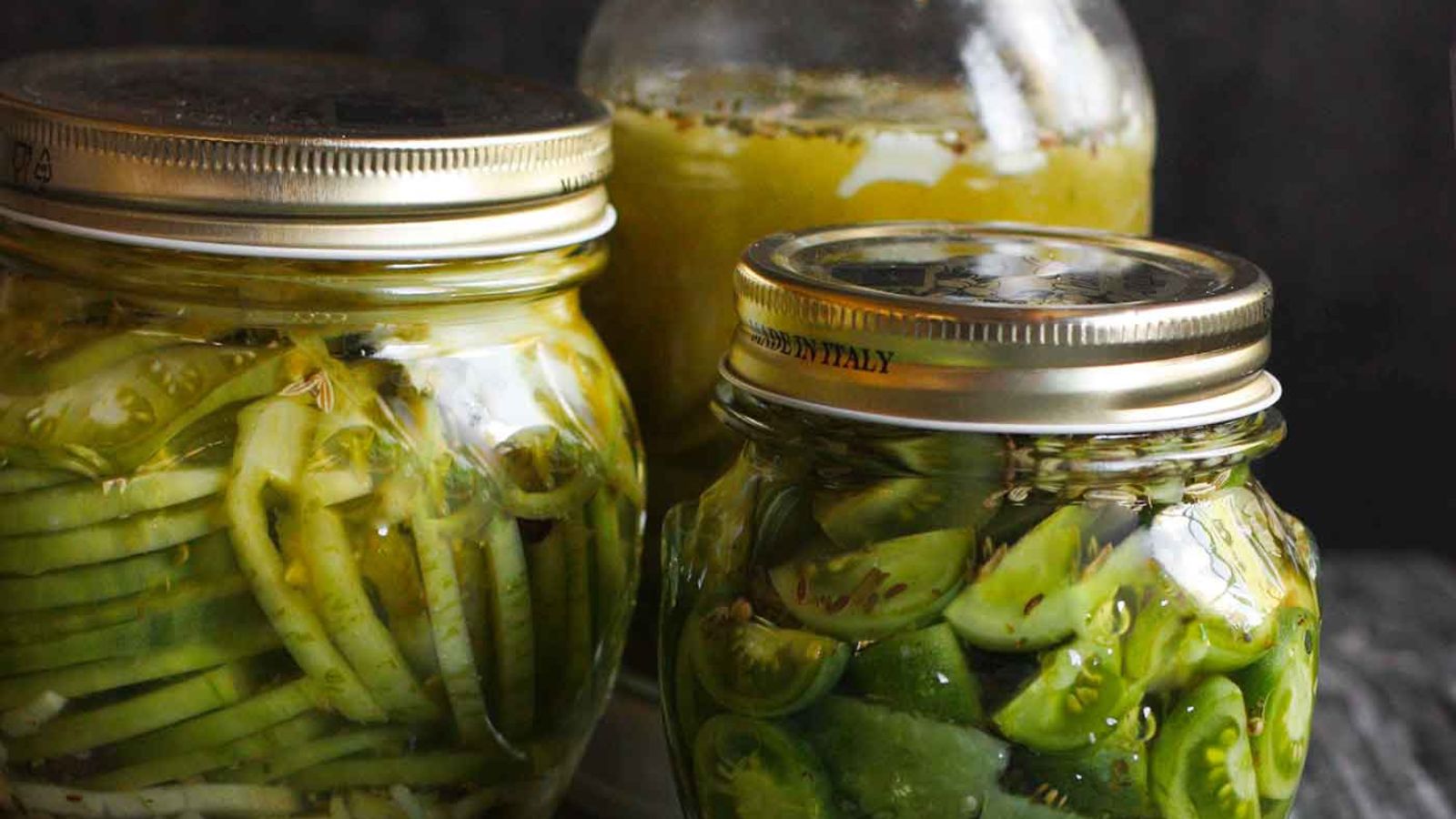 Glass jars full of green tomato pickles.