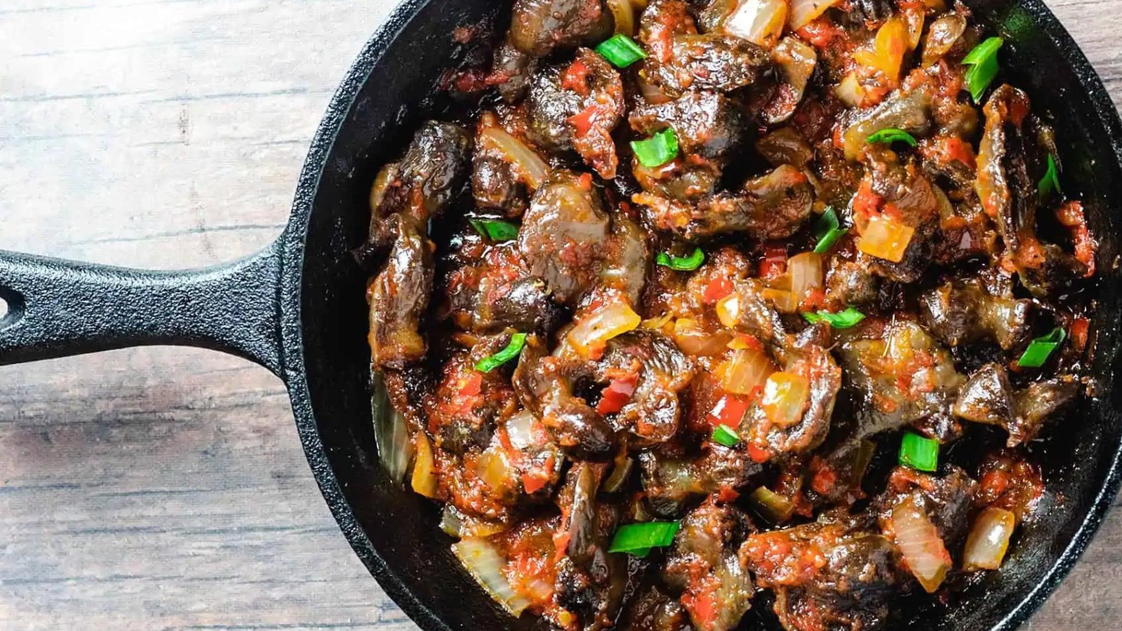 Peppered chicken gizzard fry in a cast iron pan.