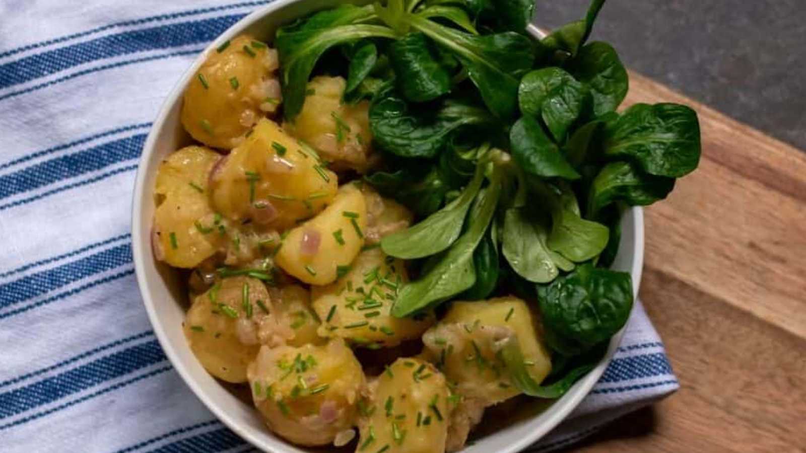 A bowl of Austrian potato salad consisting of potatoes, chicken stock, vinegar, onions, and mustard.