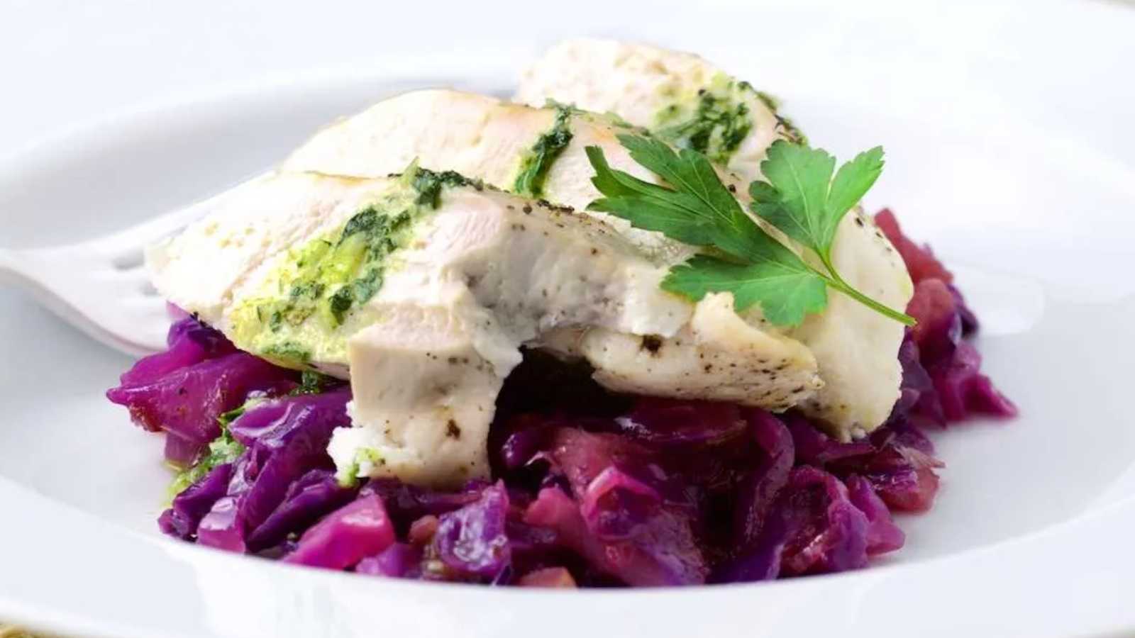 Braised red cabbage on a white plate topped with chicken breats.