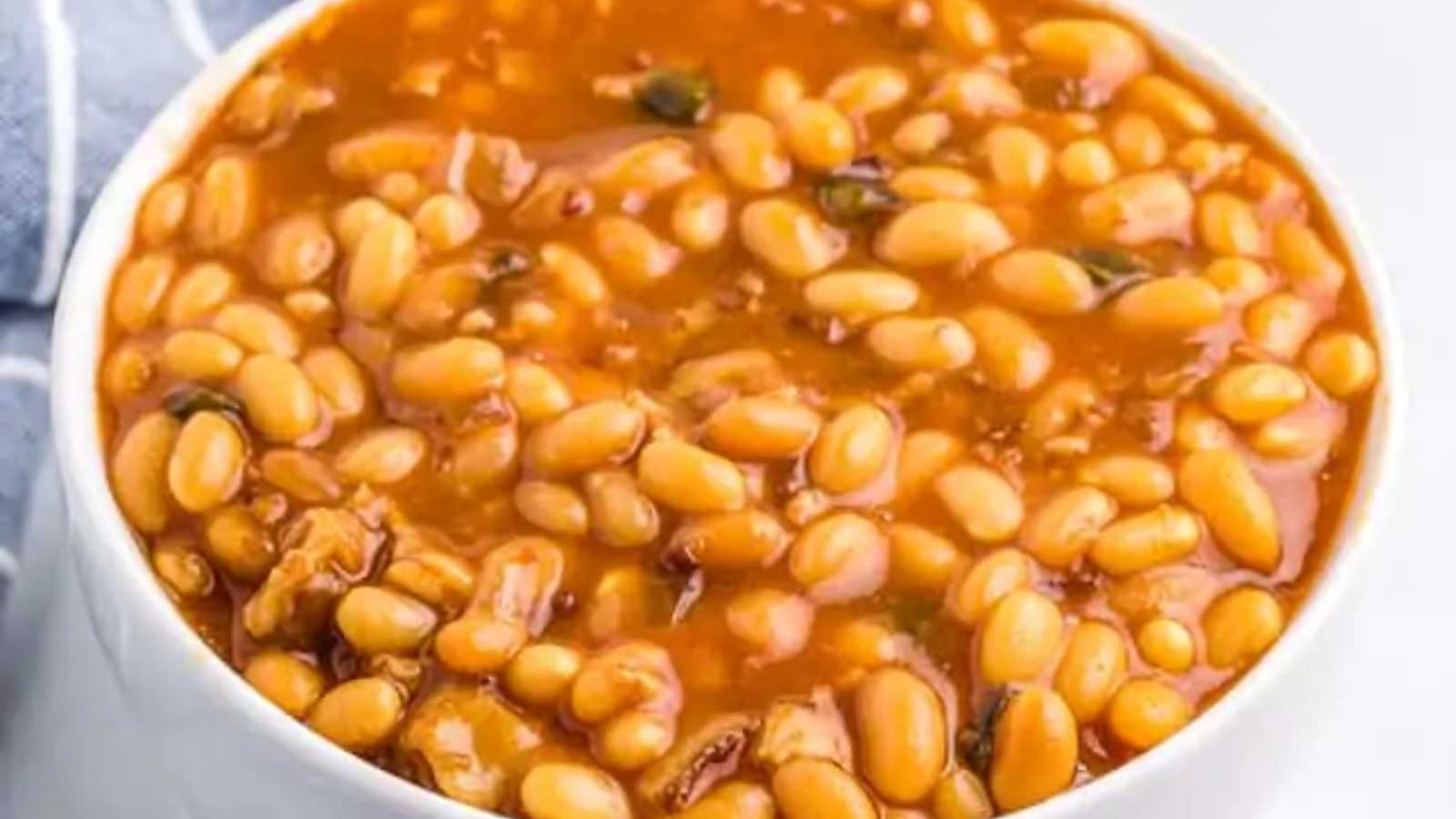 A bowl of bacon-infused baked beans, bathed in a sweet and savory sauce.