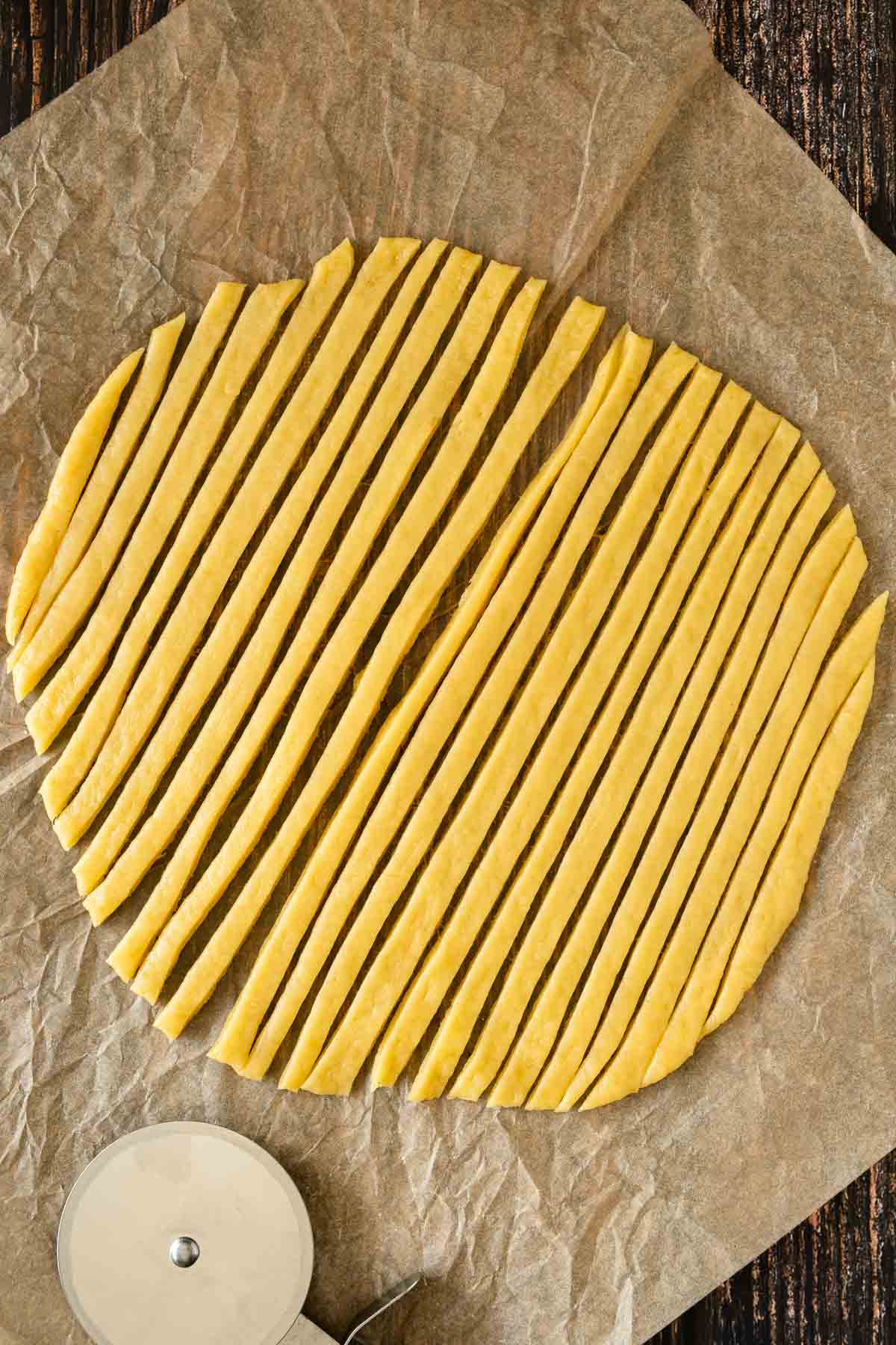 A large flat circle of dough rolled out to make noodles. It has been cut into strips of noodles for the soup.