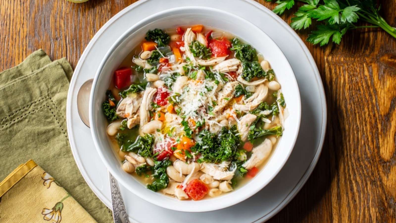 A white bowl full of shredded chicken, white beans, and vegetables in a rich broth.