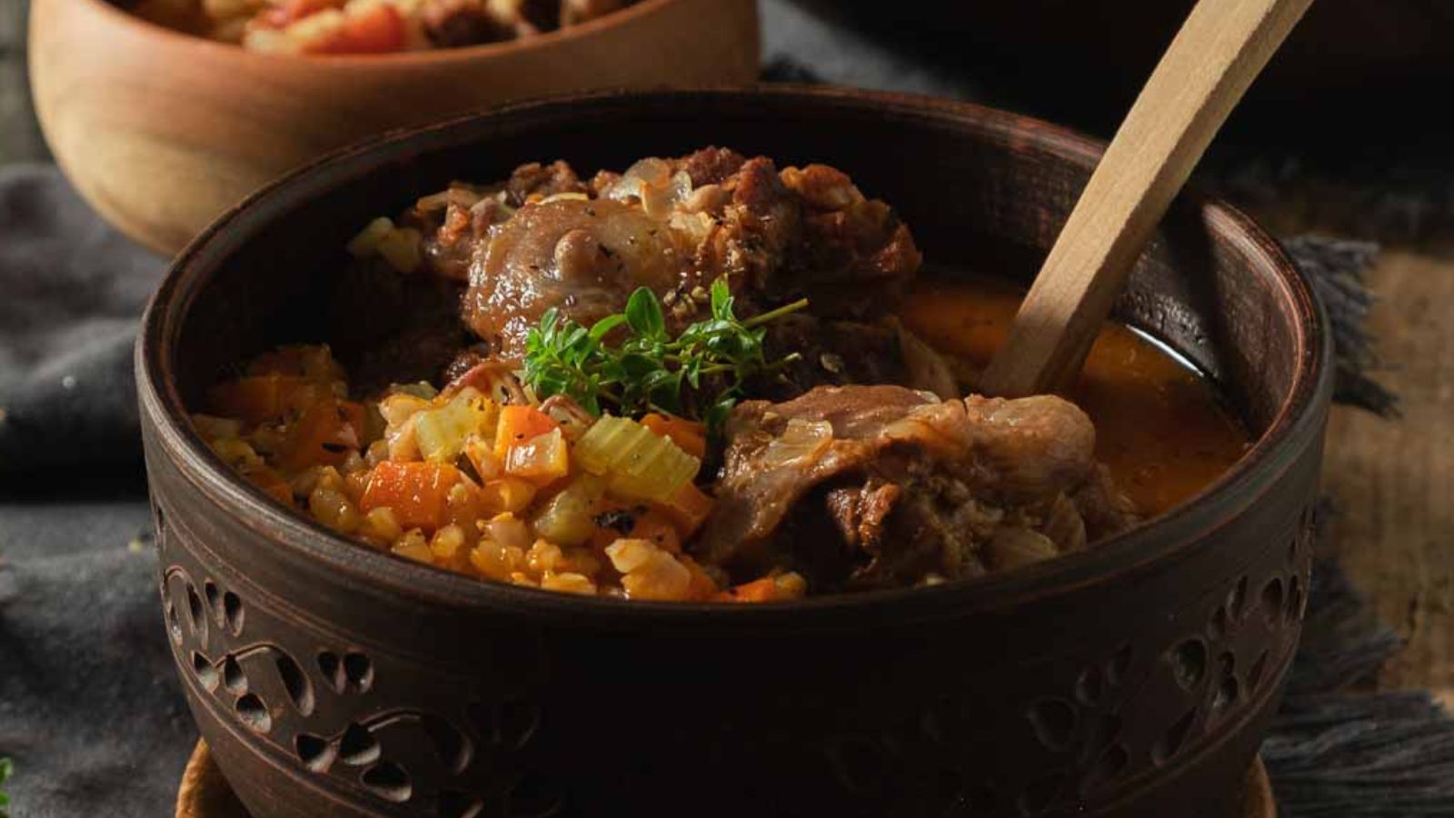 A bowl of oxtail soup with barley and vegetables.