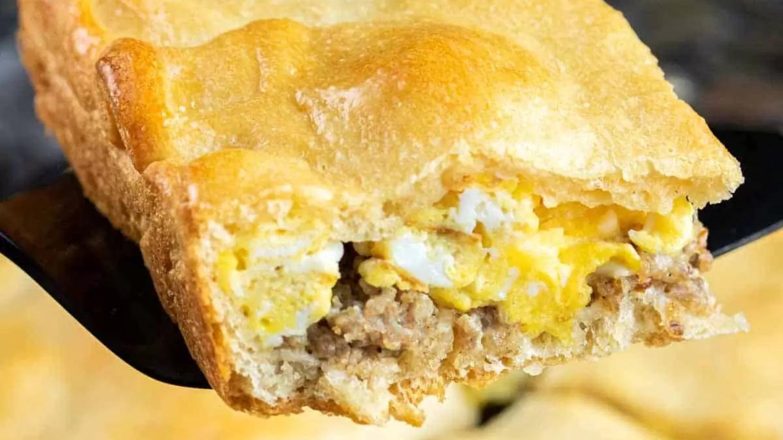 An easy eggs and sausage crescent roll breakfast casserole is layers of sausage, cream cheese, and eggs, baked into a buttery crescent roll crust.