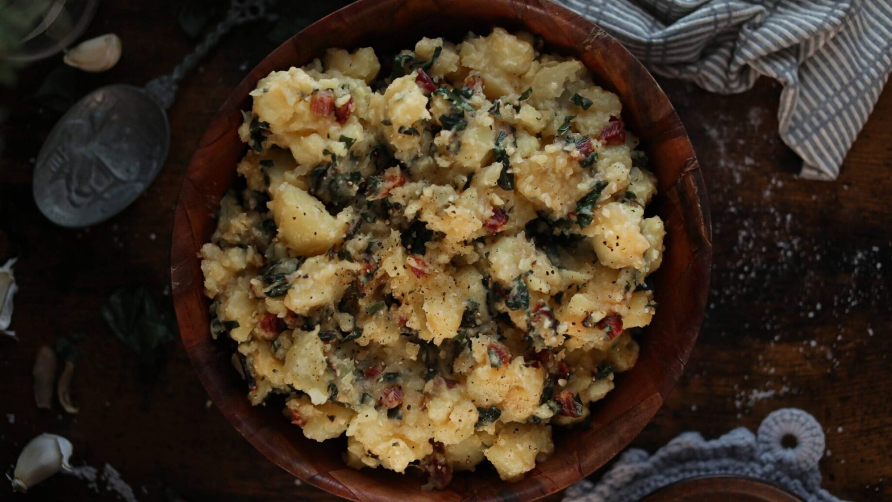 A bowl full of smashed potatoes and Swiss Chard.