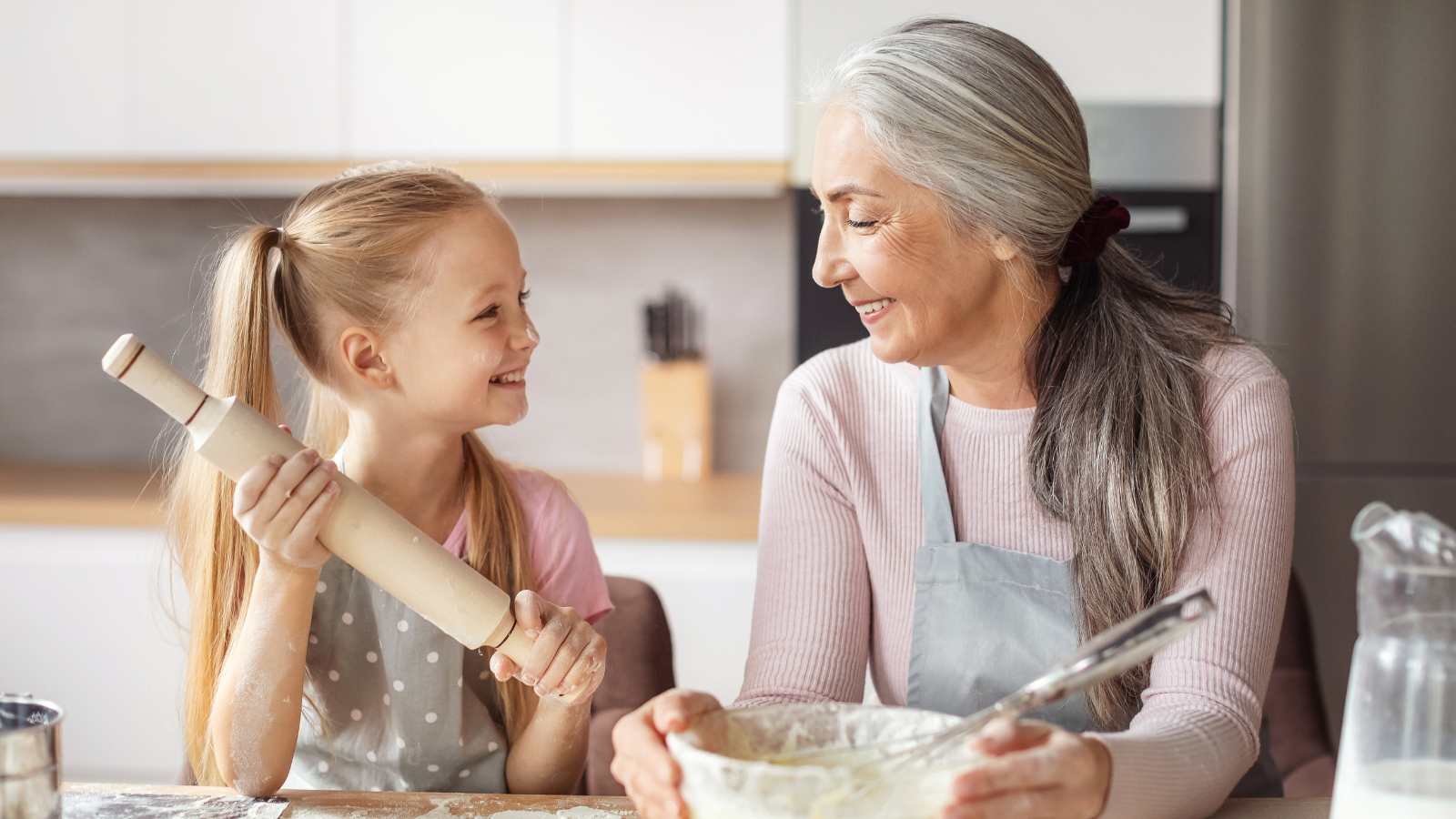 A grandmother teaches her granddaughter how to bake.
