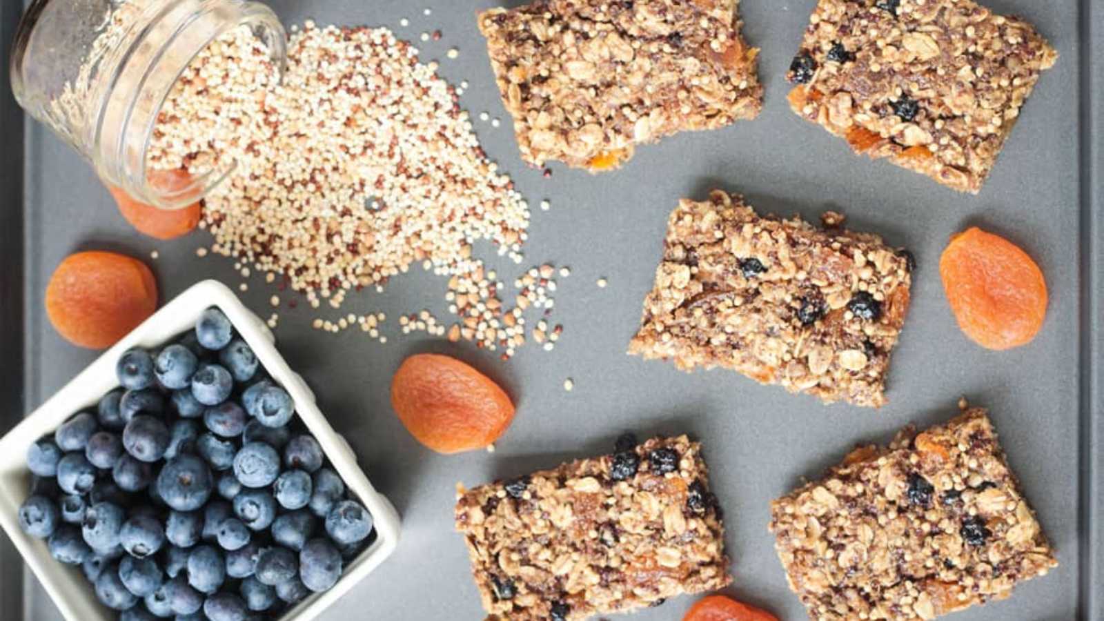A pieces of ancient grains bars blend of nutritious ancient grains, dried fruits, and nuts in a pan with a bowl of black cherries in bowl.