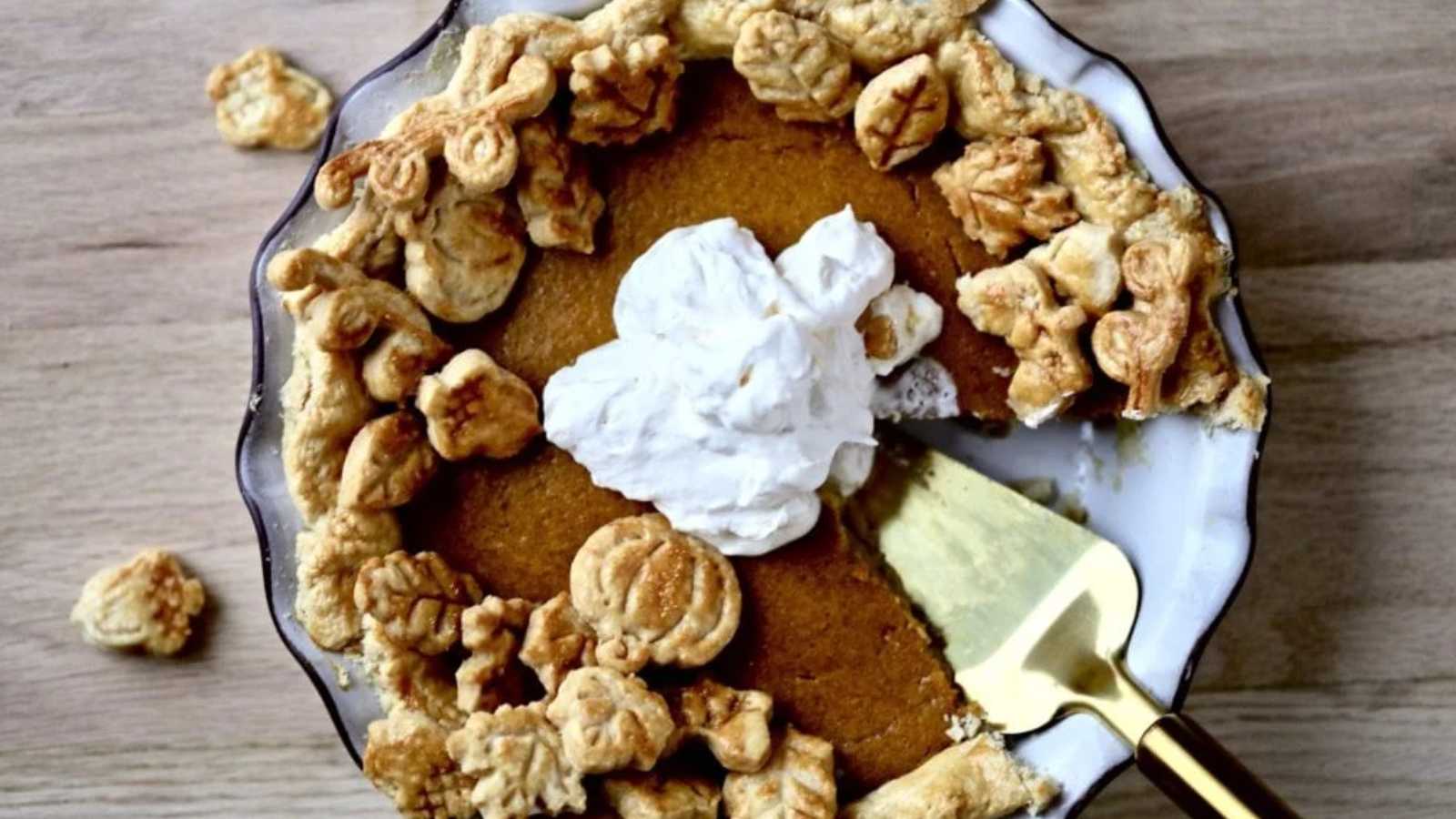 A roasted pumpkin pie topped with mini pie and cream on a plate.