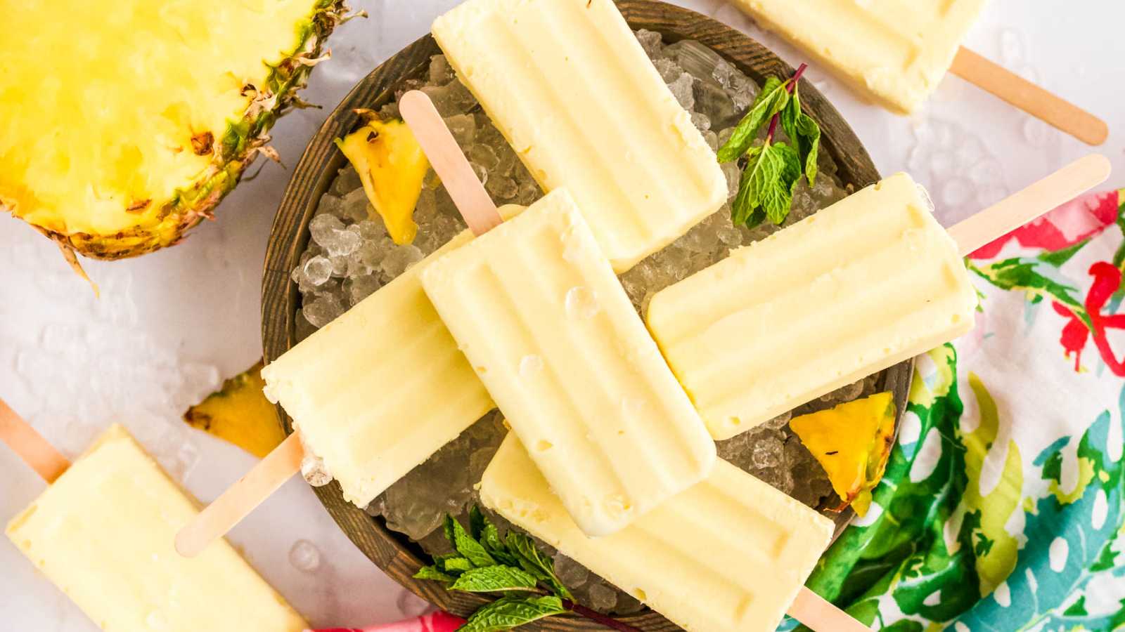 A pieces of Dole whip popsicles in a brown bowl with ice.