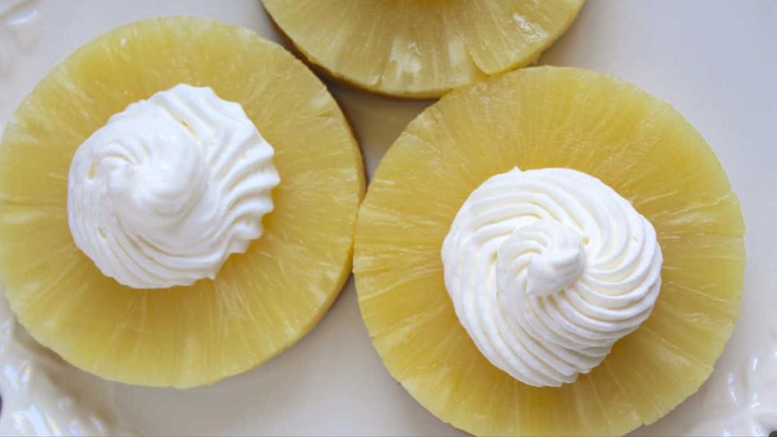 Three round pineapple with white cream topping in a plate.