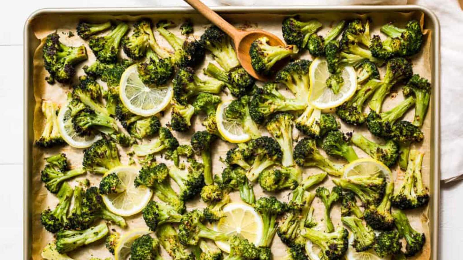 Roasted broccoli with tangy lemon slices in a baking pan.