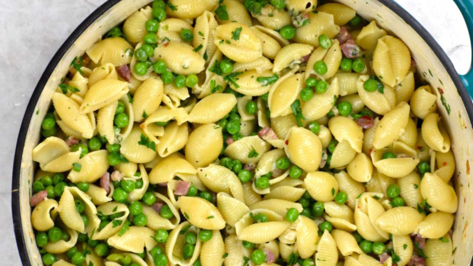 A delicious bowl of pasta with vibrant green peas and savory ham.