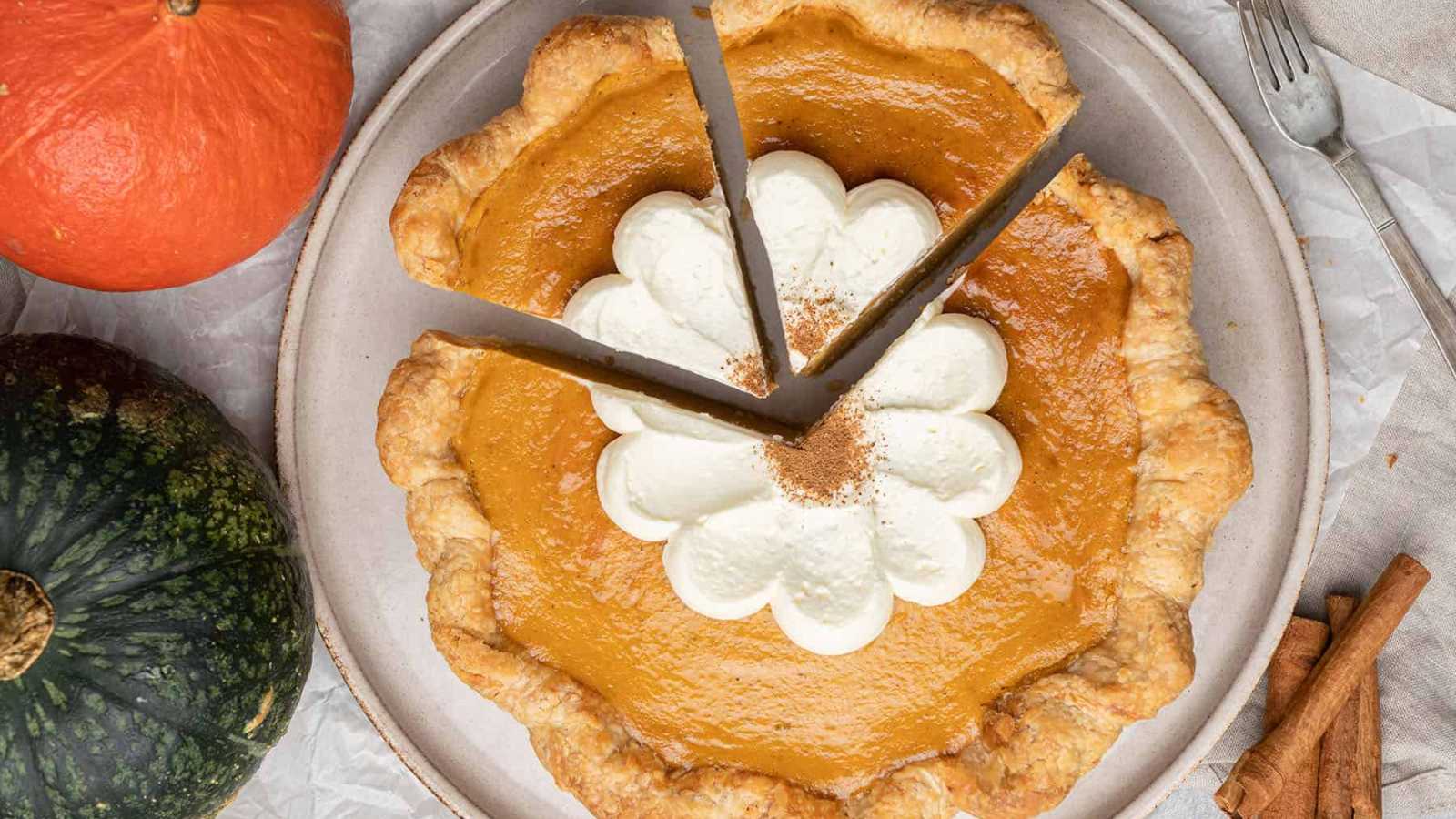 A round pumpkin pie topped with whip cream.
