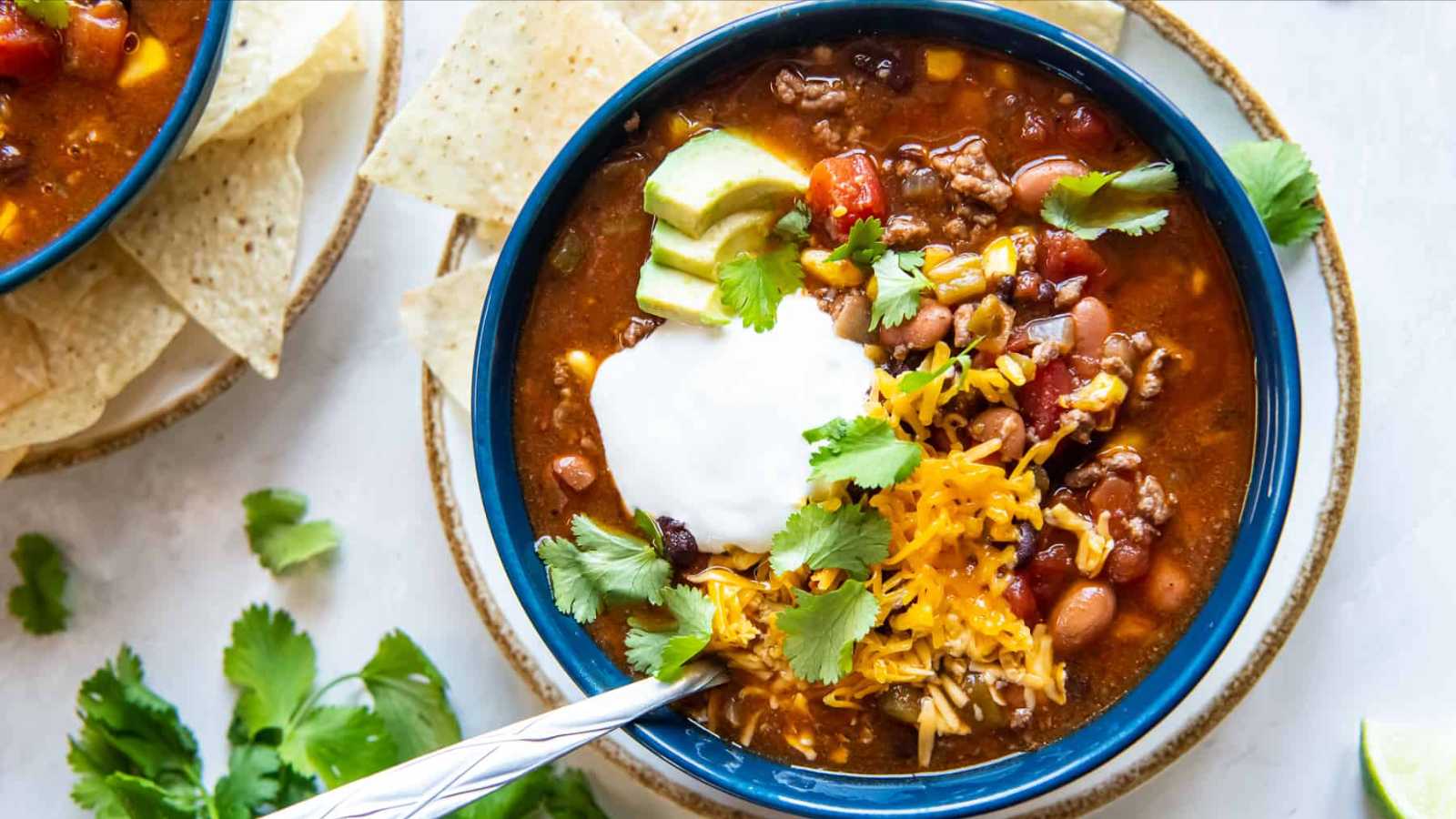 A savory bowl taco soup, topped with melted cheese and chopped cilantro.