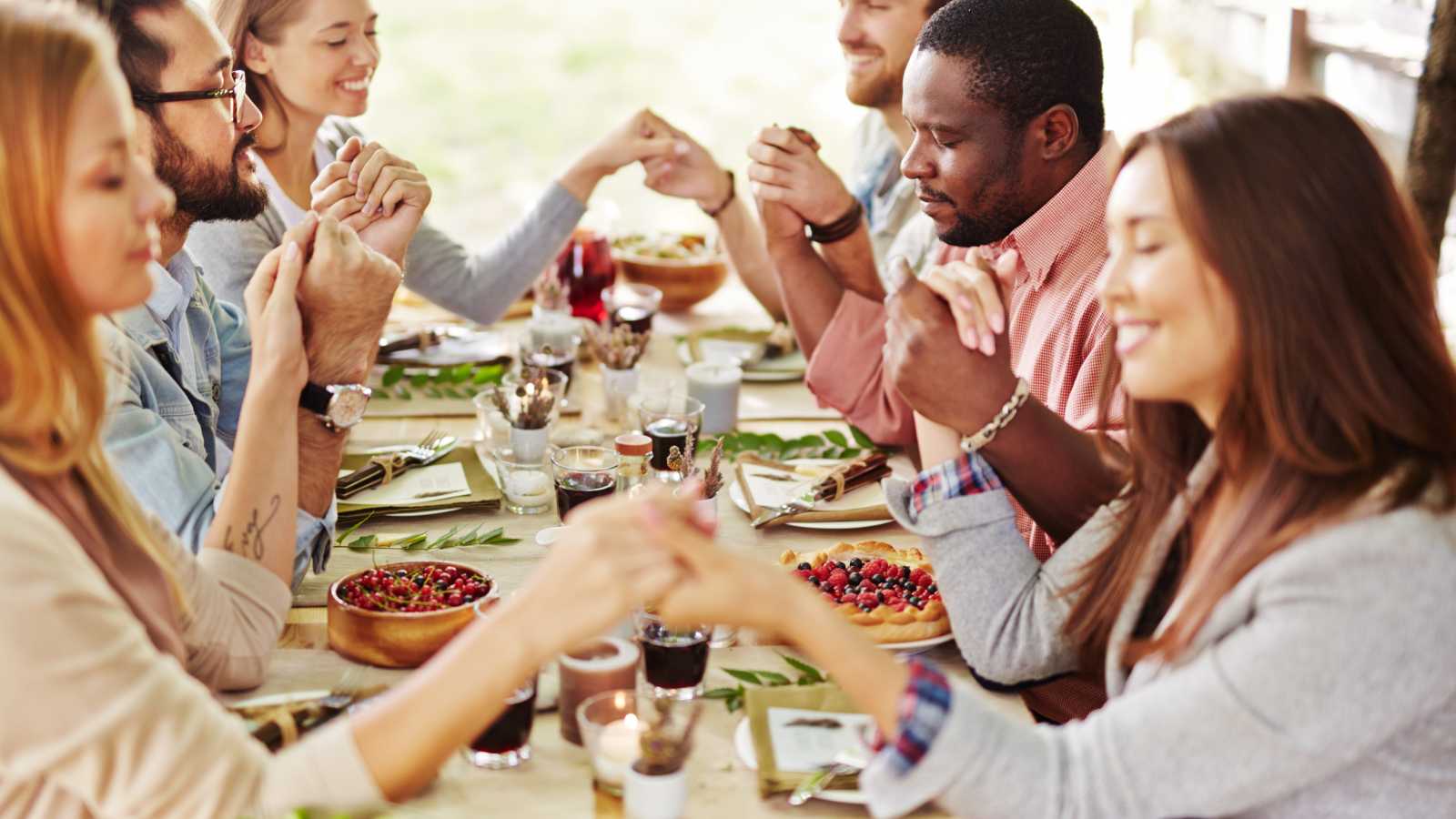 A group of friends enjoying a festive dinner together and praying.