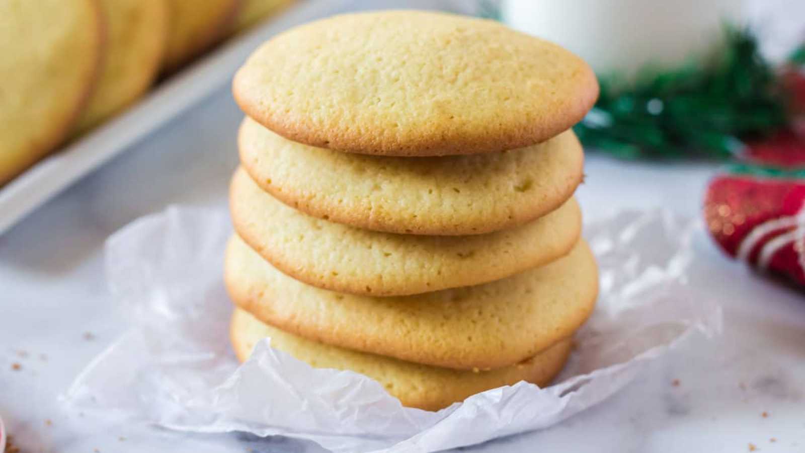 Five stacked plain sugar cookies on parchment paper.