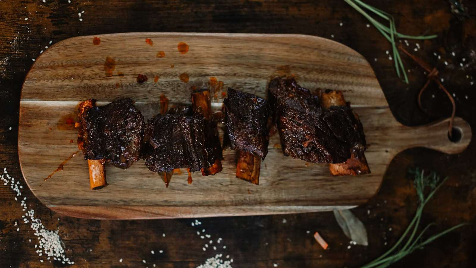 Braised beef short ribs on a wooden platter.