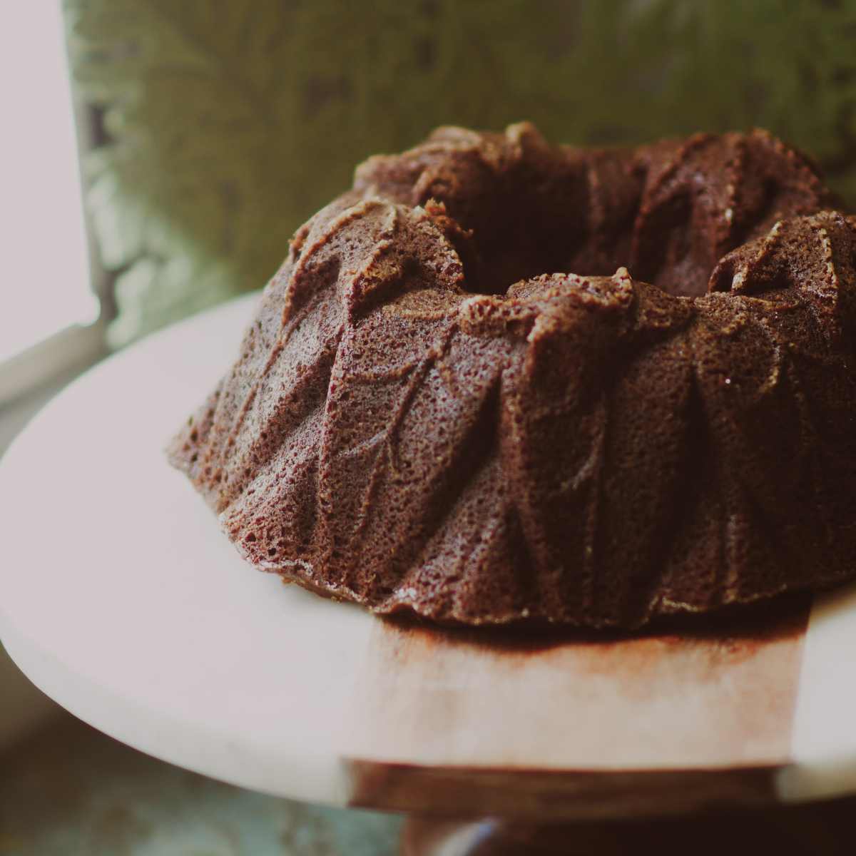 A dark pumpkin made made in an intricate bundt mold with harvest leaves.