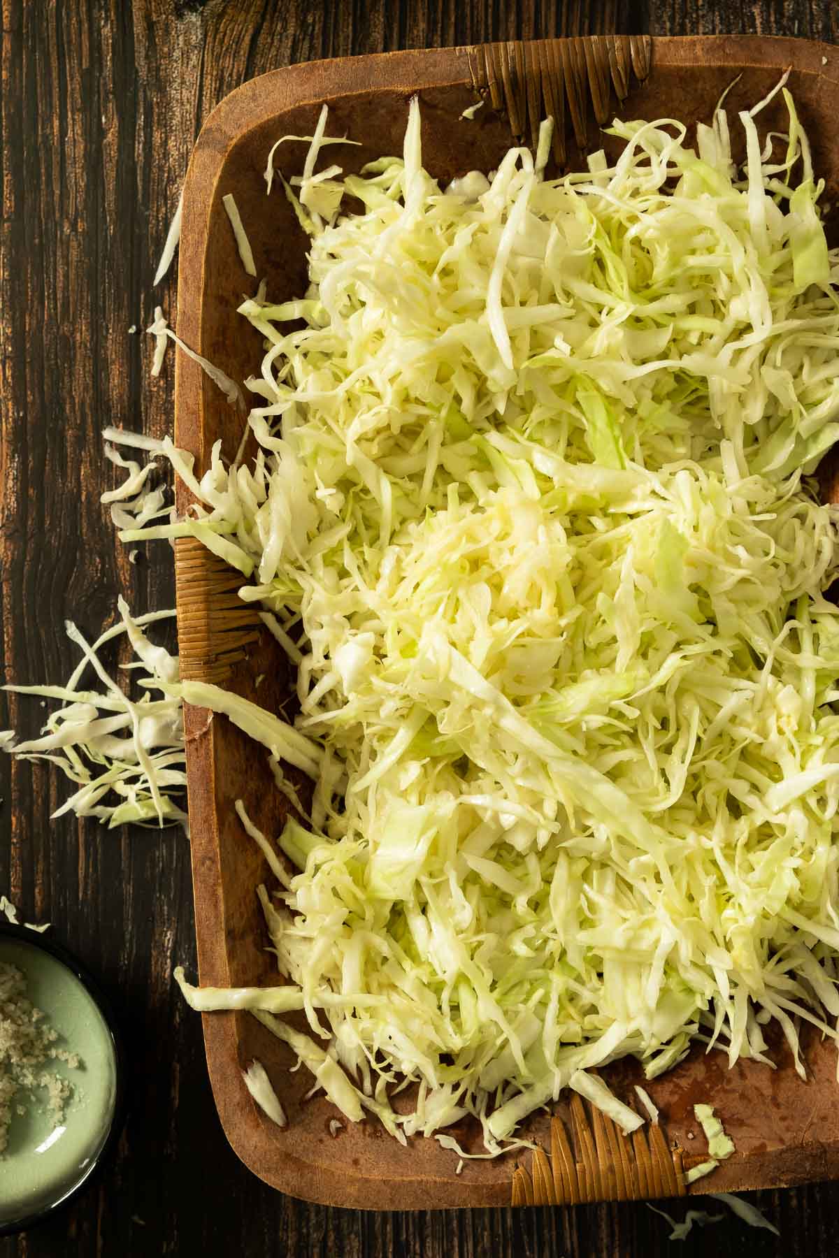 Shredded and salted cabbage in a large wooden bowl.